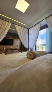 a bedroom with a large bed with white curtains at Vista Azul Apart Hotel - Vista Pedra Azul in Pedra Azul