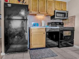 スノーシューにあるML115 Lovely Slope Side Getaway WiFi Parking Next To Villageの黒い冷蔵庫と電子レンジのあるキッチン