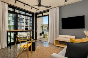 a living room with a couch and a tv on a wall at Neighbourgood 84 Harrington in Cape Town