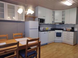 a kitchen with white appliances and a table and chairs at SAGA Modern Apartment with 24-7 Check-in in Kristiinankaupunki
