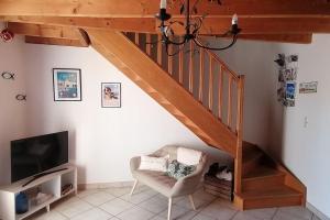 a living room with a staircase with a chair and a tv at Les Roses Trémières in Saujon
