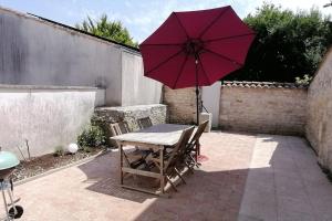 a table and chairs with a red umbrella on a patio at Les Roses Trémières in Saujon