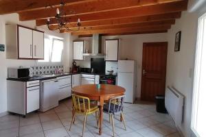 a kitchen with a wooden table and white appliances at Les Roses Trémières in Saujon +13 photos