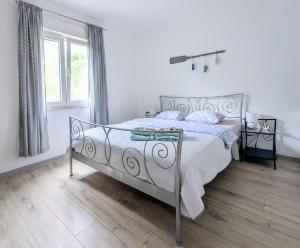 a white bedroom with a bed and a window at Apartment Sea Garden in Ičići