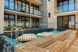 a swimming pool with a wooden deck and chairs next to a building at Neighbourgood 84 Harrington in Cape Town