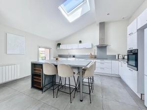 a kitchen with white cabinets and a table with stools at Le Clos Fleuri in Châtillon-sur-Chalaronne