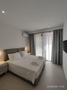 a bedroom with a large bed and a large window at Arillas Villas dinos in Arillas