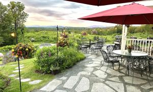 a patio with tables and chairs and an umbrella at Adair Country Inn & Restaurant in Bethlehem