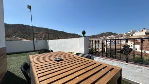 un tavolo in legno con sedie e un balcone con vista. di Piso con gran terraza en malaga arenas ad Arenas