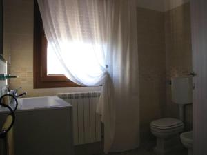 een badkamer met een toilet, een wastafel en een raam bij Corte Dante in Taglio di Po