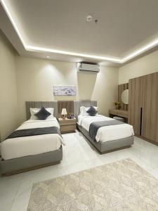 a bedroom with two beds and a air conditioner at رنز بالاس للشقق الفندقية in Dammam