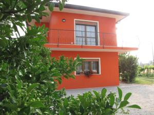 een rood huis met een balkon bij Corte Dante in Taglio di Po