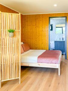 um quarto com uma cama com uma parede de madeira em Bungalow Bétula - Pichoses Camping - Gerês em Rio Caldo