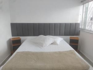 a bedroom with a large bed with white sheets at Apto 2 quartos Nucleo Bandeirante in Brasilia