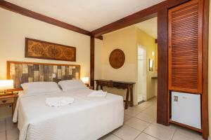 a bedroom with a large white bed and a desk at Pousada Bonns Ventos in Ilhabela +46 photos