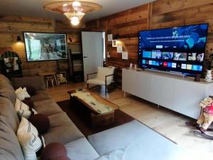 ein Wohnzimmer mit einem großen Flachbildfernseher in der Unterkunft Chalets De La Grande Ourse - Sublime Chalet 16 personnes avec sauna & Jacuzzi ! MAE-8951 in La Plagne Tarentaise + 9 Fotos