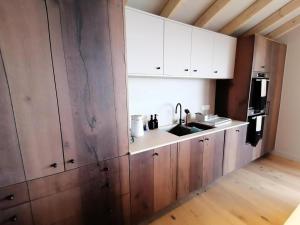 eine Küche mit weißen Schränken und einem Waschbecken in der Unterkunft Chalets De La Grande Ourse - Sublime Chalet 16 personnes avec sauna & Jacuzzi ! MAE-8951 in La Plagne Tarentaise