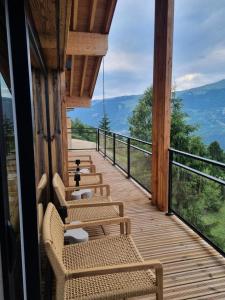 eine Veranda mit Stühlen und Blick auf die Berge in der Unterkunft Chalets De La Grande Ourse - Sublime Chalet 16 personnes avec sauna & Jacuzzi ! MAE-8951 in La Plagne Tarentaise