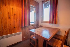 une salle à manger avec une table en bois et deux fenêtres dans l'établissement Résidence Portail G - PORTAIL 73 MAE-5911, à Valmorel