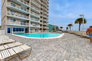 un hombre caminando por una piscina al lado de un edificio en Tradewind 1204, en Orange Beach