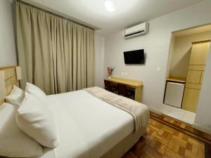 a bedroom with a white bed and a desk at Hotel Monte Alegre in Rio de Janeiro +47 photos