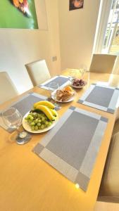 a wooden table with a plate of fruit and wine glasses at Pool, drinks and a hot tub! in Northampton