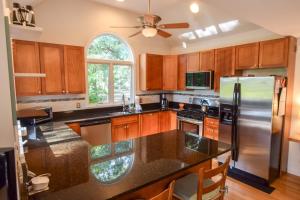 Una cocina con gabinetes de madera y un refrigerador de acero inoxidable. en Outdoor entertaining re-imagined Enjoy a new luxury back yard, en Eastham