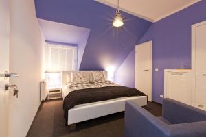 a purple bedroom with a bed and a chair at Café Pension Steffen in Sanitz