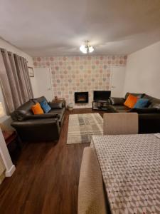 a living room with two leather couches and a fireplace at Howe Holiday homes in Stromness