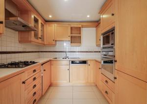 a kitchen with wooden cabinets and a stove top oven at Two bed Two bath Kensington Apartment in London