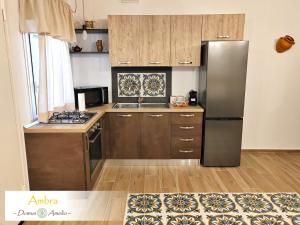 a kitchen with a stainless steel refrigerator and wooden cabinets at Domus Amelio - Country Rooms in Cinisi +60 photos