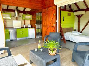 a room with a kitchen and a bed and a table at La Petite Créole - Bungalow de standing in Petit-Bourg