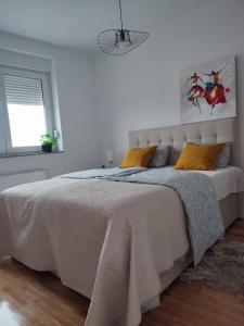 a white bedroom with a large bed with yellow pillows at Apartment DIVA, private parking in Osijek +13 photos
