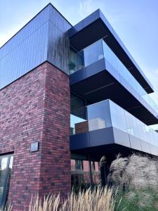 a red brick building with a black at Apartament WHITE GLOVE Deluxe Warmiński Port in Olsztyn