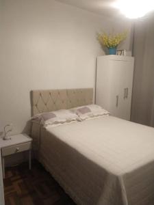una camera con letto e frigorifero bianco di Apartamento de praia a Capão da Canoa