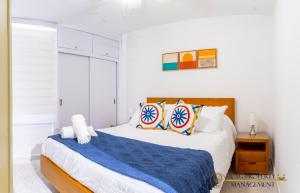 a white bedroom with a bed with blue sheets and pillows at Coco Paraiso Baranquilla - Hermosos Apartamentos Cercanos Al Malecón Del Rio in Barranquilla +37 photos