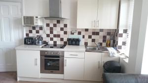 a small kitchen with white cabinets and a sink at Strathmore Apartments in Lytham St Annes