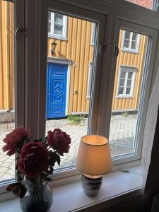 a window with a lamp and flowers on a window sill at Koselig studioleilighet i sentrum in Trondheim