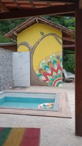 a pool with a painting on the side of a building at Chalé no Sana - Conforto e Aconchego in Sana