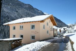 un edificio con nieve en el suelo junto a una montaña en Haus Leo, en Kappl