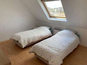 two beds in a small bedroom with a window at Jolie maison de vacances in Concarneau +29 photos