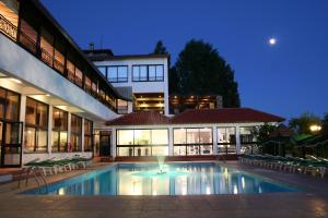 a swimming pool in front of a building at night at Rodon Hotel and Resort in Agros