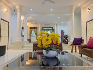 a living room with a vase with yellow flowers on a glass table at Homestay VillaSolihin Sungai Buloh in Sungai Buluh