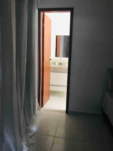 an open door leading to a bathroom with a mirror at Apartamento encantador em Rio das Ostras in Rio das Ostras