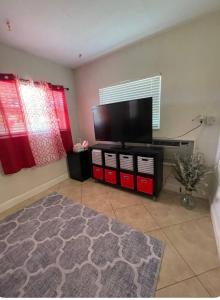 a living room with a flat screen tv on a entertainment center at Private room with shared bathroom in Hollywood area in Dania Beach