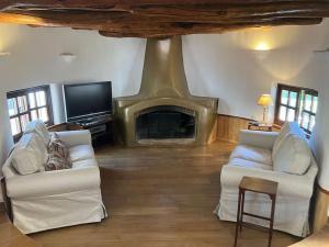 a living room with two white couches and a fireplace at Cortijo Pago y Benisalte- a Stylish villa set within beautiful mountain views in Órgiva
