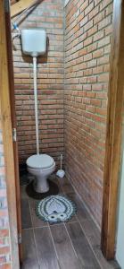 ein Badezimmer mit Toilette und einer Ziegelwand in der Unterkunft Casa de campo Campo Alegre SC 11 Hóspedes in Campo Alegre + 17 Fotos
