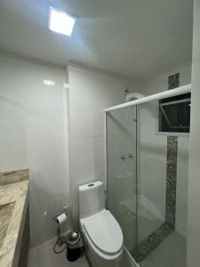 a white bathroom with a toilet and a shower at Apartamento Porto Belo - Perequê in Perequê