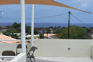 a patio with a white wall and chairs and an umbrella at My Shelter in Willemstad