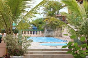 a swimming pool with a waterfall and palm trees at Farol das Gaivotas Pousada e Residence in Caraguatatuba
